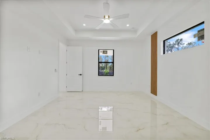 Unfurnished room featuring recessed lighting, a tray ceiling, ceiling fan, and light marble finish floors