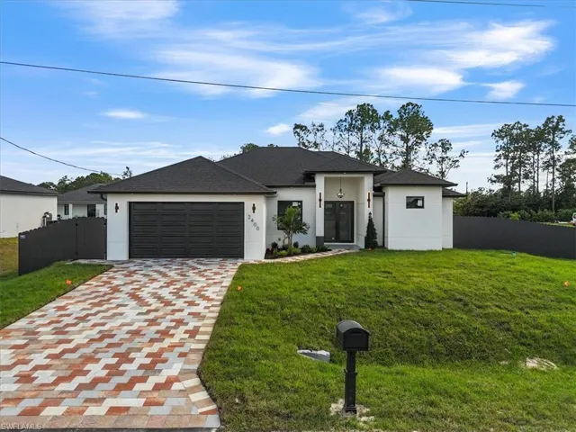 View of front facade featuring stucco siding, decorative driveway, a garage, and roof with shingles
