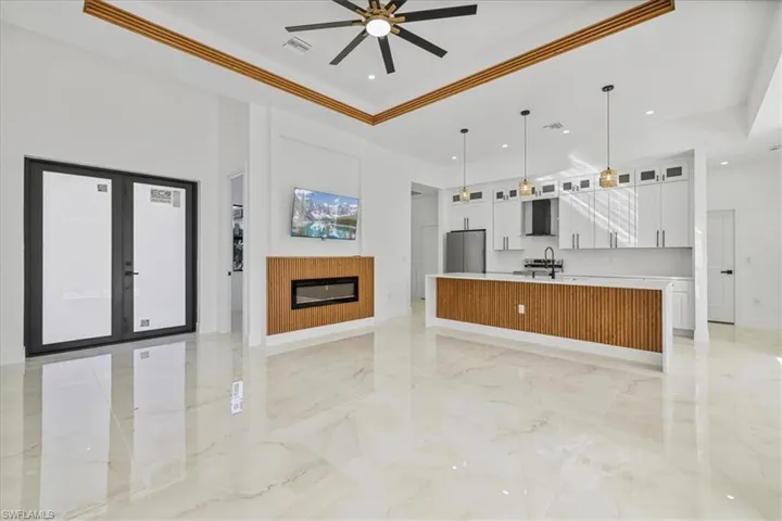 Kitchen featuring open floor plan, glass insert cabinets, a spacious island, a raised ceiling, and white cabinetry
