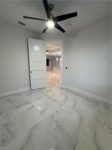 Empty room featuring light marble finish flooring and ceiling fan