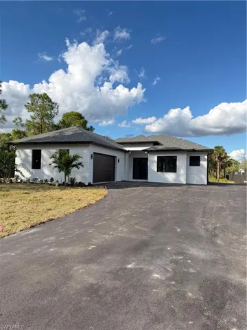 View of front of home featuring driveway, a garage, roof with shingles, and a front yard