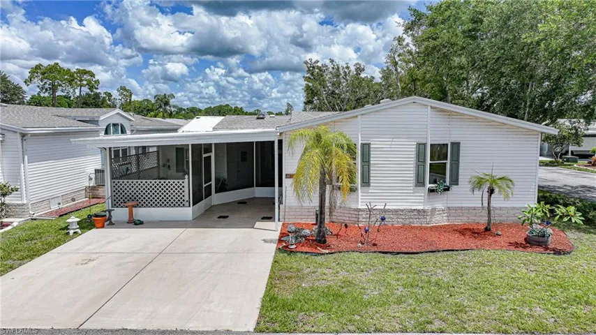 White siding exterior featuring a covered carport, screened-in porch with lattice detailing, and mature landscaping