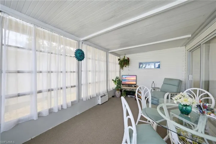 Enclosed patio with full-height windows, a textured ceiling, durable carpet flooring, and sliding glass doors