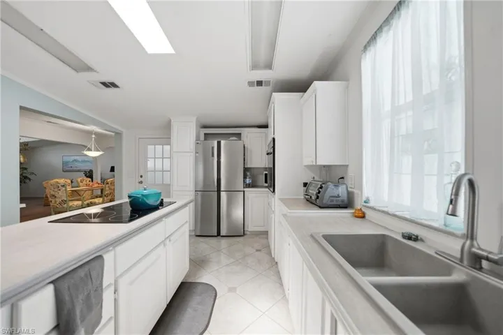 Contemporary kitchen featuring white cabinetry, light-toned countertops, and a dual basin sink with a gooseneck faucet