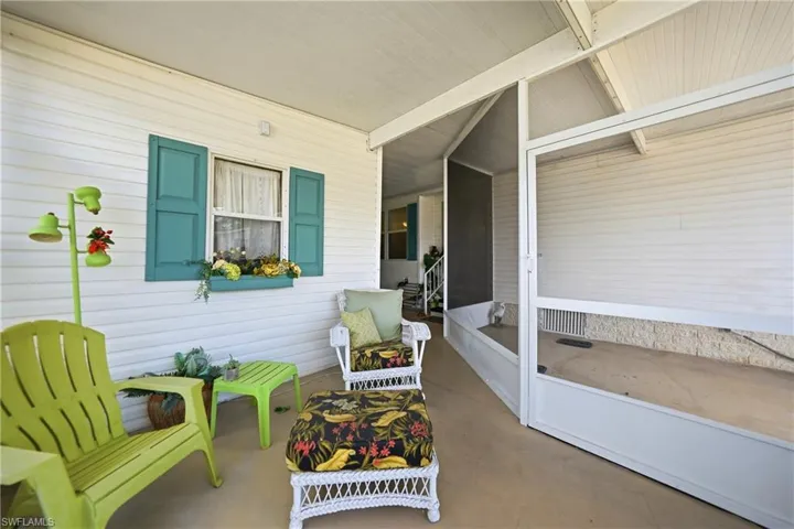 Covered patio featuring a solid concrete floor, white siding exterior, window with teal shutters, and a screened enclosure