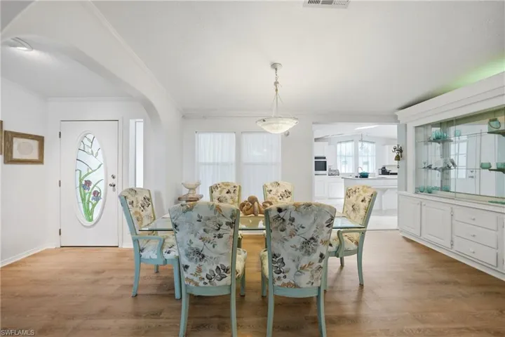 Dining area featuring wood-finish flooring, a built-in display cabinet with glass shelving, and an overhead light fixture