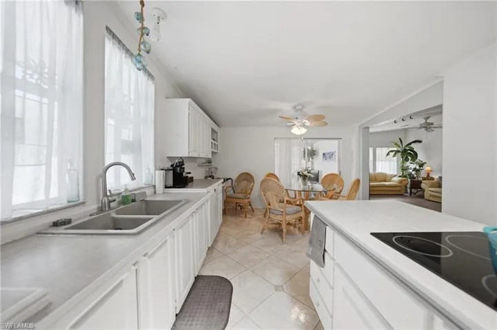 Kitchen featuring white cabinetry, a double basin stainless steel sink, light-toned countertops, and a built-in cooktop