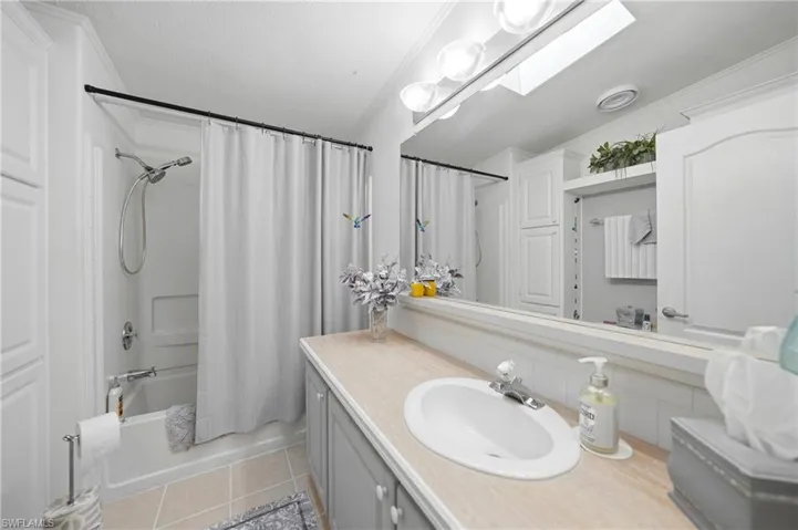 Full bathroom featuring a tub/shower combination with a shower curtain, an oval undermount sink, a wood-finish countertop, and integrated storage cabinetry