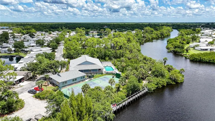 Expansive waterfront property featuring a two-story clubhouse, outdoor swimming pool, and multiple tennis courts