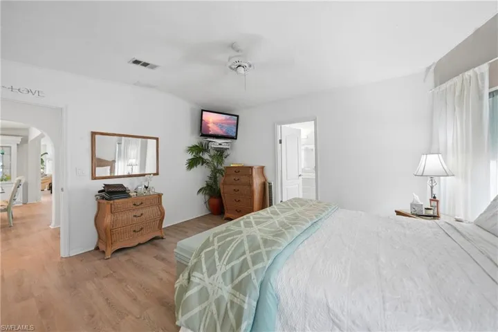 Spacious room featuring wood-finish flooring, white walls, and a ceiling fan