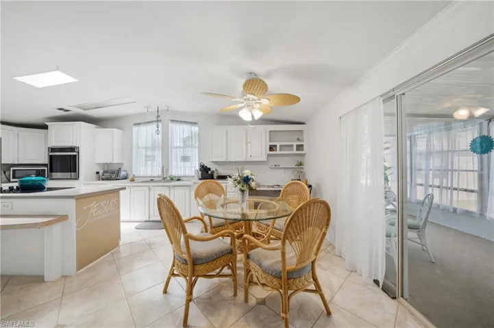 Kitchen and dining area featuring white cabinetry, integrated appliances, tile flooring, and a ceiling fan