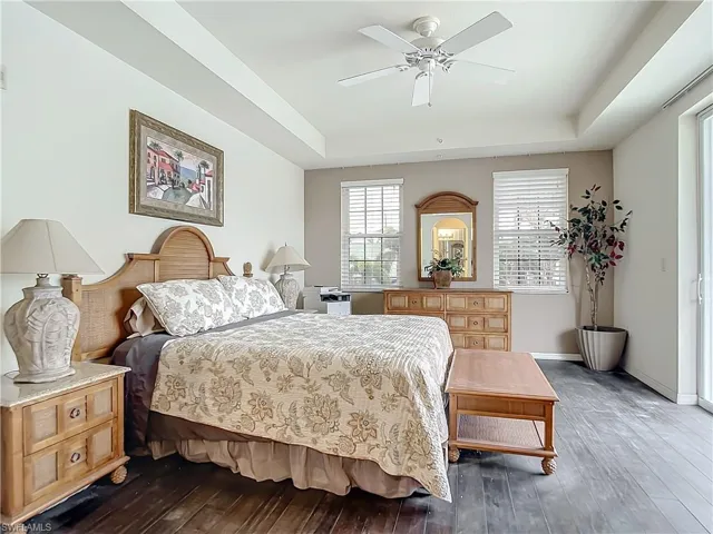 Bedroom with a tray ceiling, ceiling fan, and dark hardwood / wood-style flooring