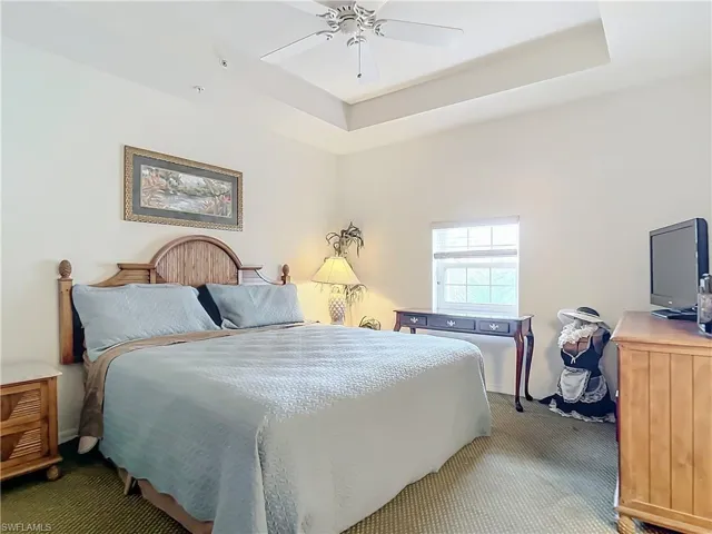 Guest Bedroom featuring carpet flooring, a tray ceiling, and ceiling fan