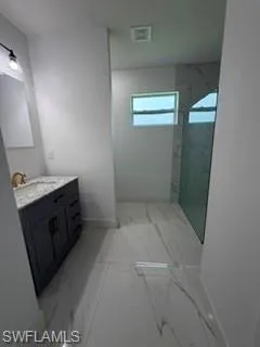 Contemporary bathroom featuring a single vanity with stone countertop, undermount sink, and gold-finish faucet
