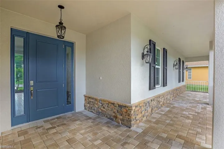 Property entrance featuring stone siding, stucco siding, and a porch