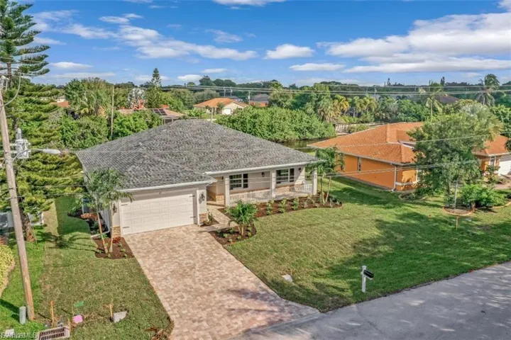 Single story home featuring a front yard, an attached garage, driveway, and covered porch