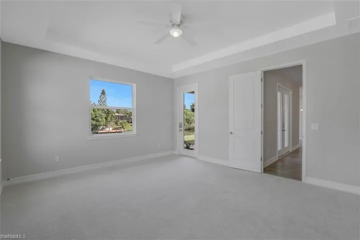 Carpeted empty room with a tray ceiling and a ceiling fan