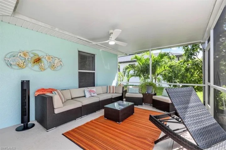Screened outdoor living area with a ceiling fan, light blue exterior wall, and concrete flooring