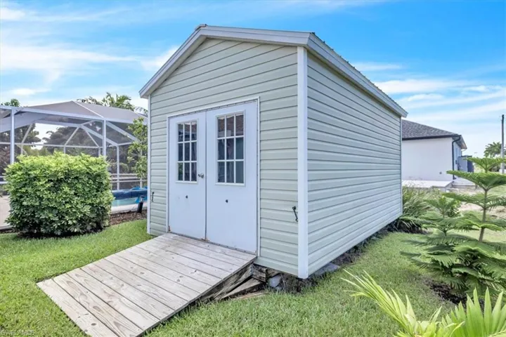 Exterior storage shed with double doors, wood-finish ramp, and vinyl siding