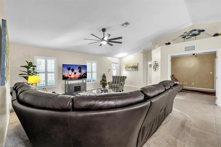 Vaulted ceiling, ceiling fan, plantation shutters, tile flooring, and an arched entryway