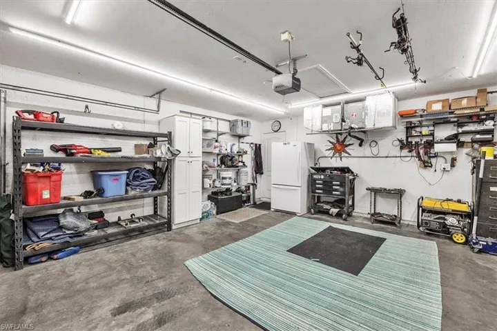 Spacious garage with concrete flooring, overhead lighting, and built-in white cabinetry