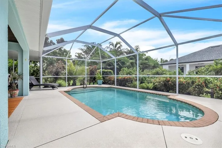 Screened enclosure featuring a curved-edge swimming pool with steps, a paver coping, and ample deck space