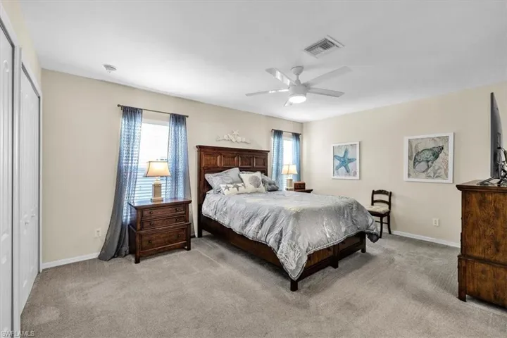 Wall-to-wall carpeting, window with blinds and drapes, ceiling fan with integrated lighting, and neutral wall tones
