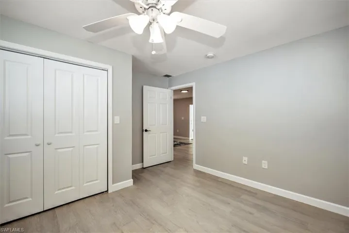 Unfurnished bedroom featuring a closet, baseboards, light wood-style floors, and ceiling fan