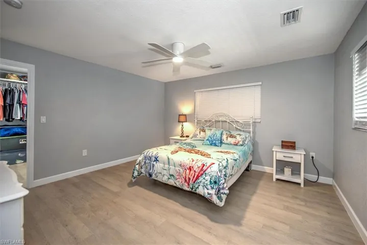 Bedroom with baseboards, visible vents, wood finished floors, and a ceiling fan