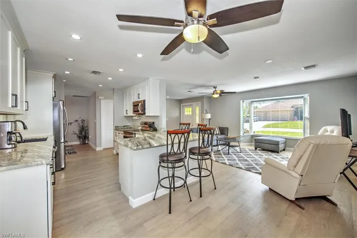 Kitchen with a sink, a ceiling fan, a breakfast bar, open floor plan, and stainless steel appliances