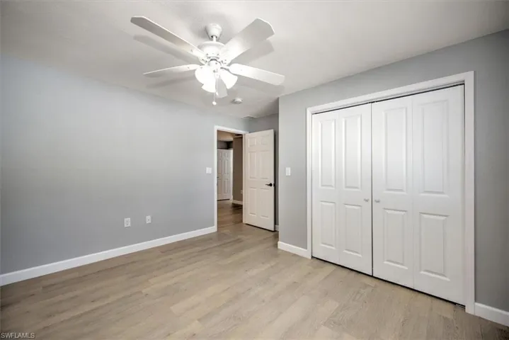 Unfurnished bedroom with light wood finished floors, baseboards, a closet, and a ceiling fan