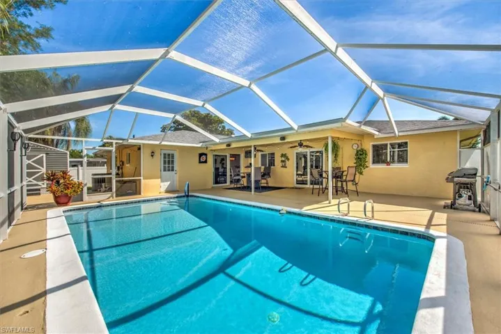 Pool featuring glass enclosure, ceiling fan, grilling area, and a patio area