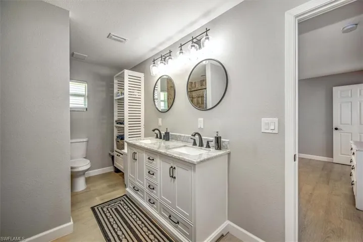 Bathroom with toilet, a sink, baseboards, and wood finished floors