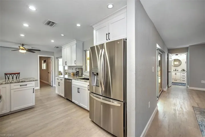 Kitchen with white cabinetry, stainless steel appliances, ceiling fan, light wood-style flooring, and visible vents