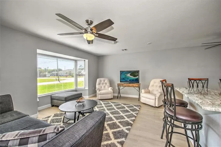 Living area with visible vents, baseboards, light wood finished floors, and ceiling fan