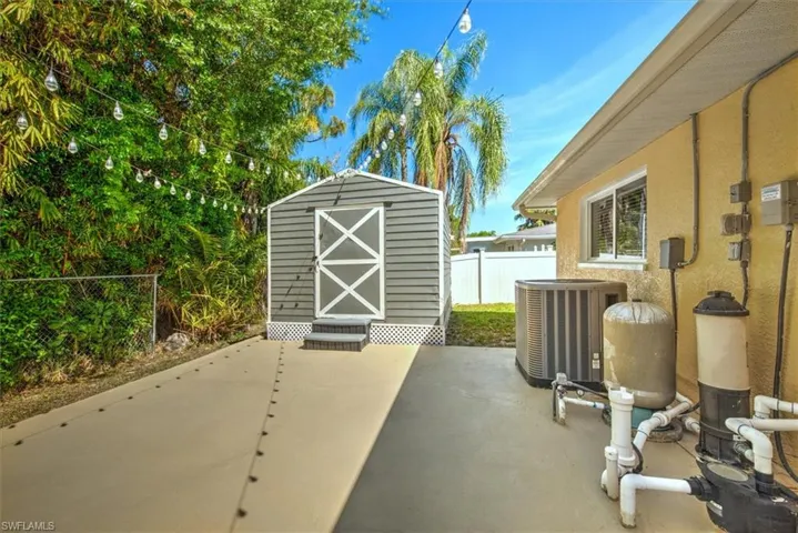 View of patio featuring an outbuilding, central AC unit, a fenced backyard, and a storage shed