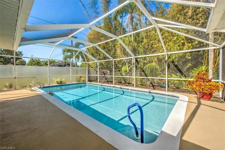 View of swimming pool with a fenced in pool, glass enclosure, fence, and a patio