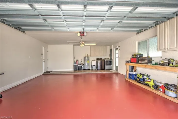 Garage with baseboards, a garage door opener, a ceiling fan, water heater, and washer and clothes dryer