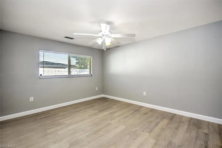 Unfurnished room with baseboards, visible vents, wood finished floors, and a ceiling fan