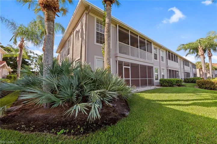 Back of house with a sunroom, a yard, stucco siding, and a balcony