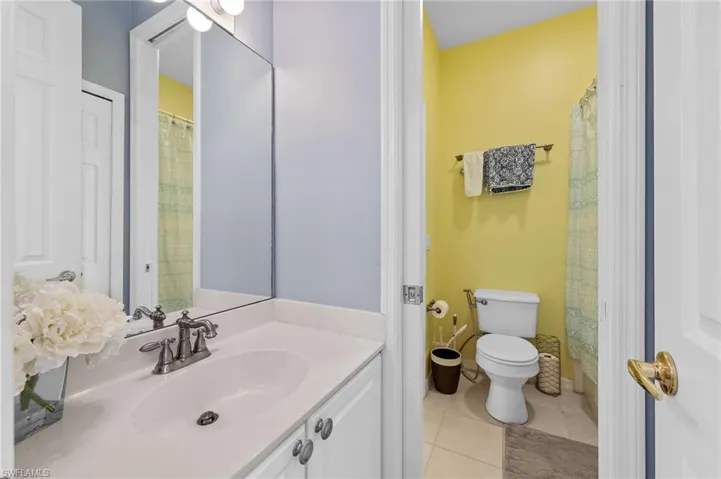 Full bath with vanity, light tile patterned floors, and curtained shower