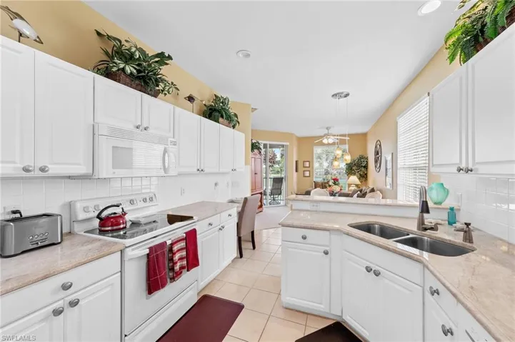 Kitchen featuring tasteful backsplash, white appliances, white cabinetry, and recessed lighting