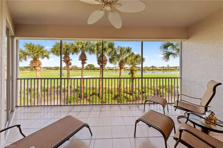 Sunroom with a textured wall, tile patterned flooring, golf course view, and a water view