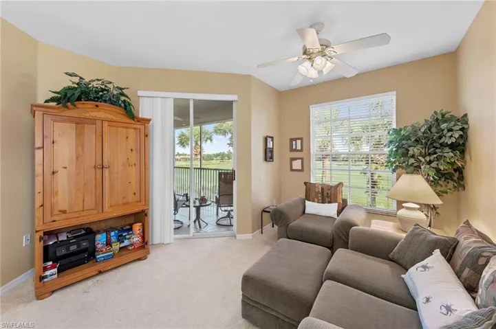 Living area with light colored carpet, plenty of natural light, and ceiling fan
