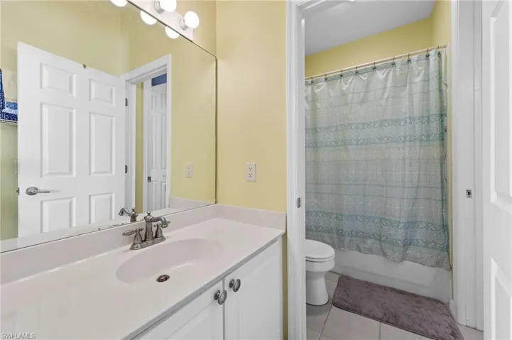 Bathroom featuring vanity, light tile patterned floors, and shower / bath combination with curtain