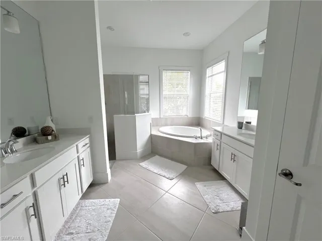 Bathroom featuring vanity, tiled tub, and tile patterned floors