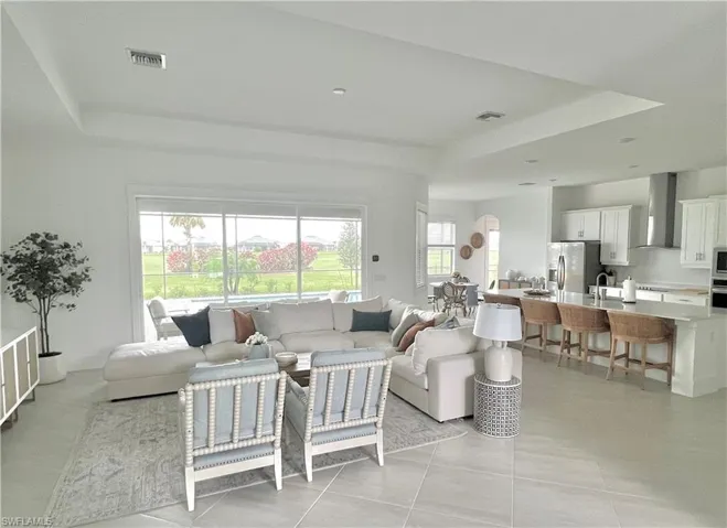 Living room featuring light tile patterned flooring, sink, and a tray ceiling