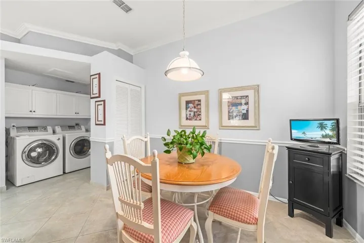 Dining area featuring independent washer and dryer, ornamental molding, baseboards, and light tile patterned flooring