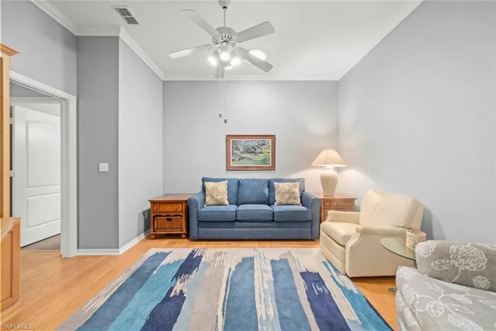 Living area with light wood-style flooring, a ceiling fan, crown molding, and baseboards
