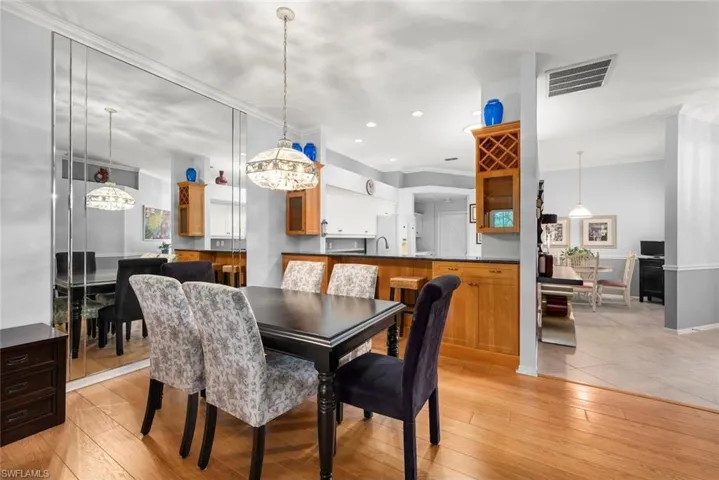 Dining room with ornamental molding, light wood-style flooring, and recessed lighting